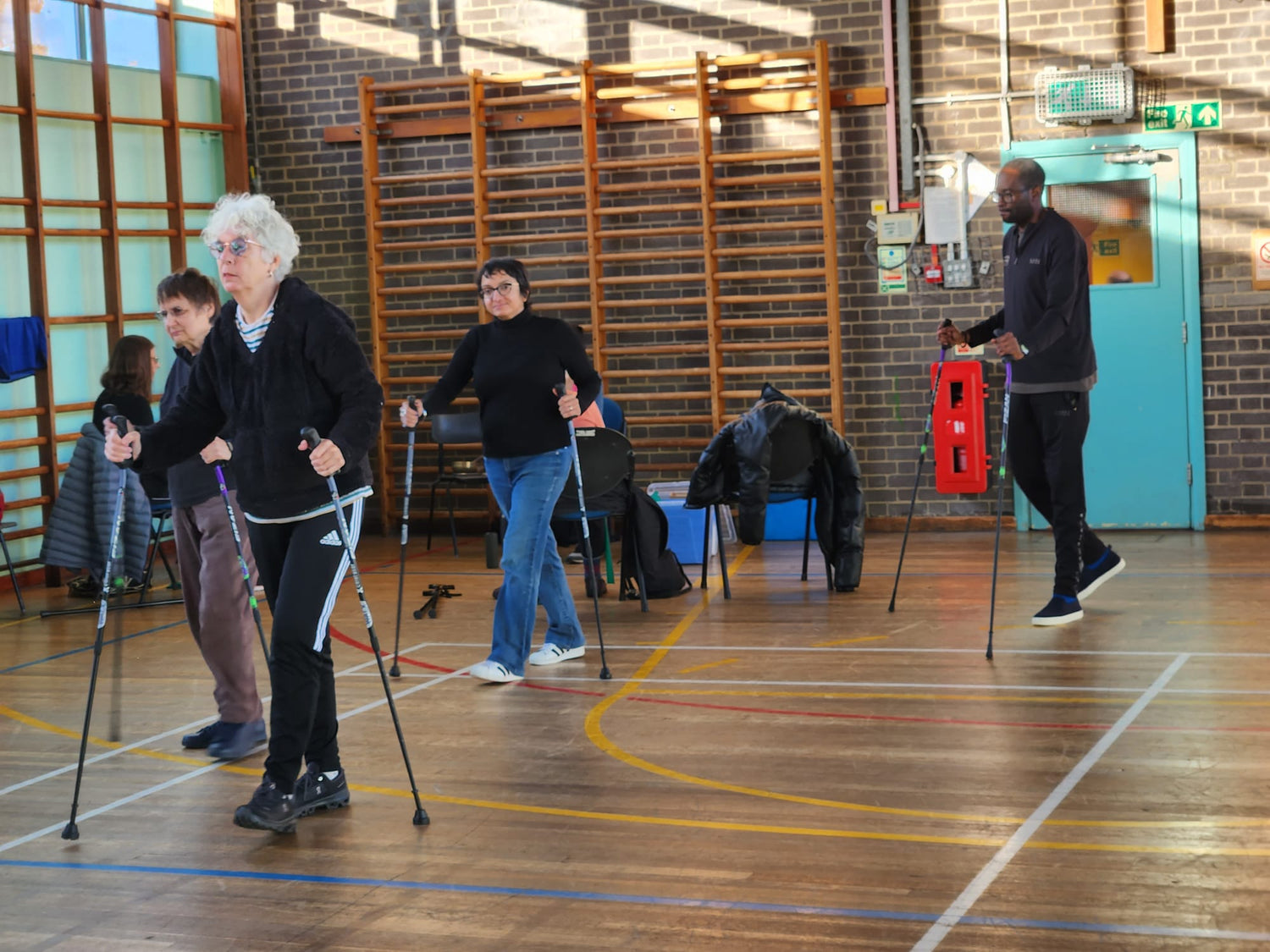 Group of people using WALX Poles in a gymnasium setting