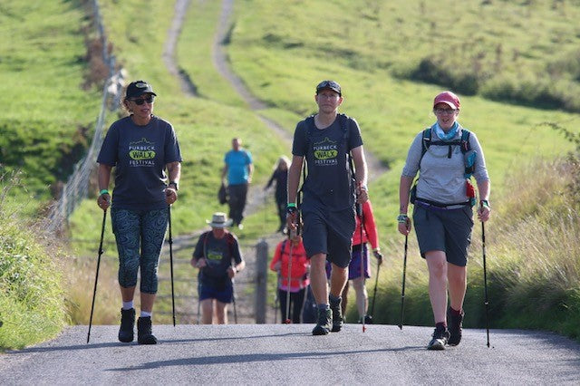 Group of people hiking on a trail with greenery in the background