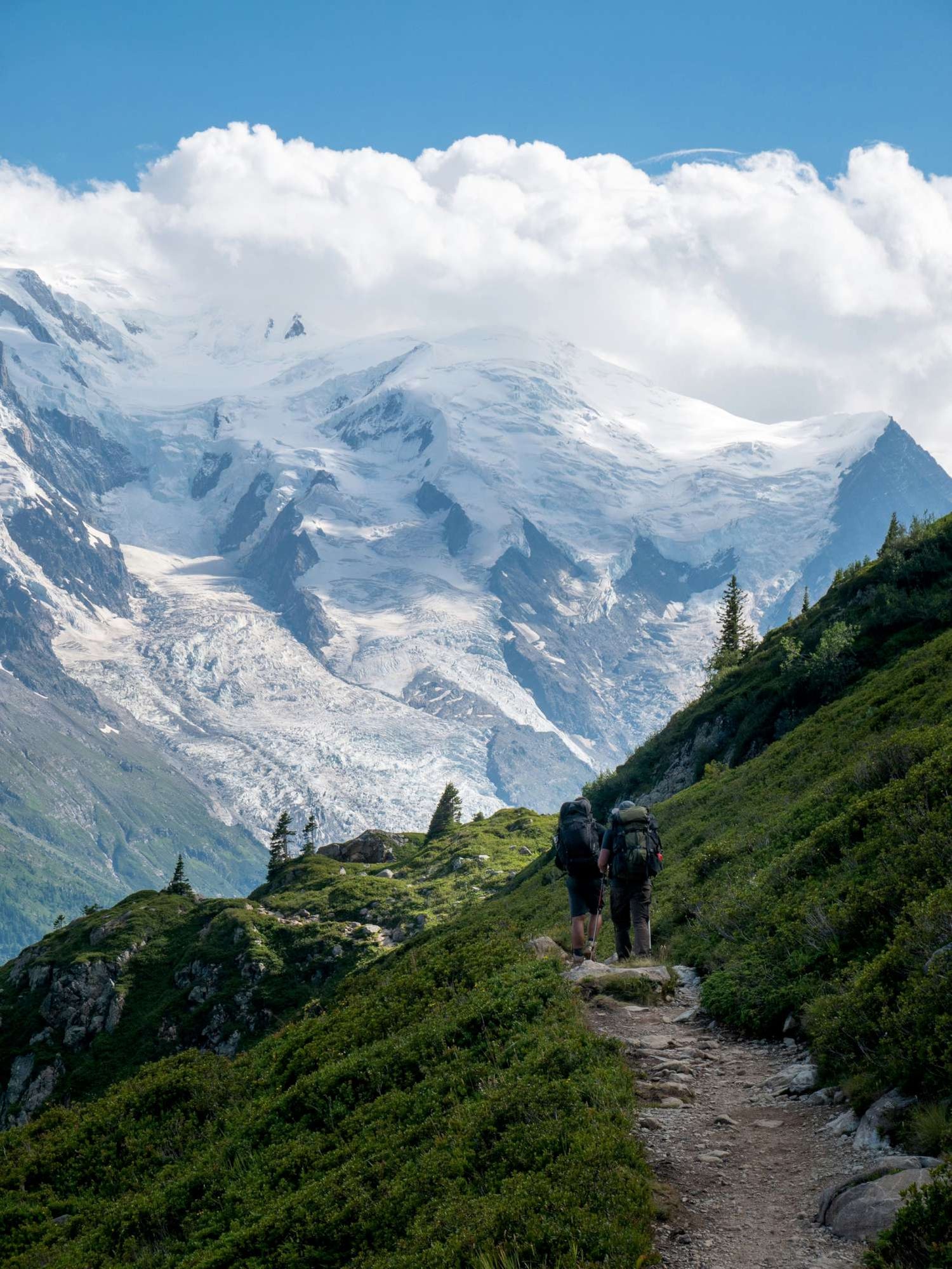 Two hikers on a trail with Mont Blanc in the background