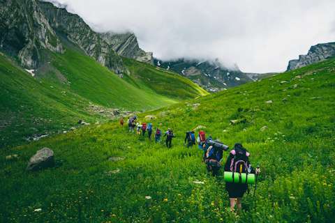 Group of hikers with backpacks on a grassy mountain slope